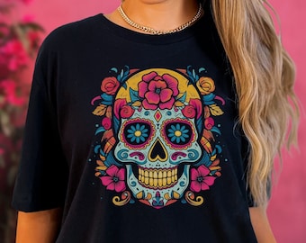 May include: Black t-shirt featuring a colourful sugar skull design. The skull has pink flowers, blue eyes, and yellow accents. The text "See size chart. For oversized look go up a few sizes." is printed on the image.