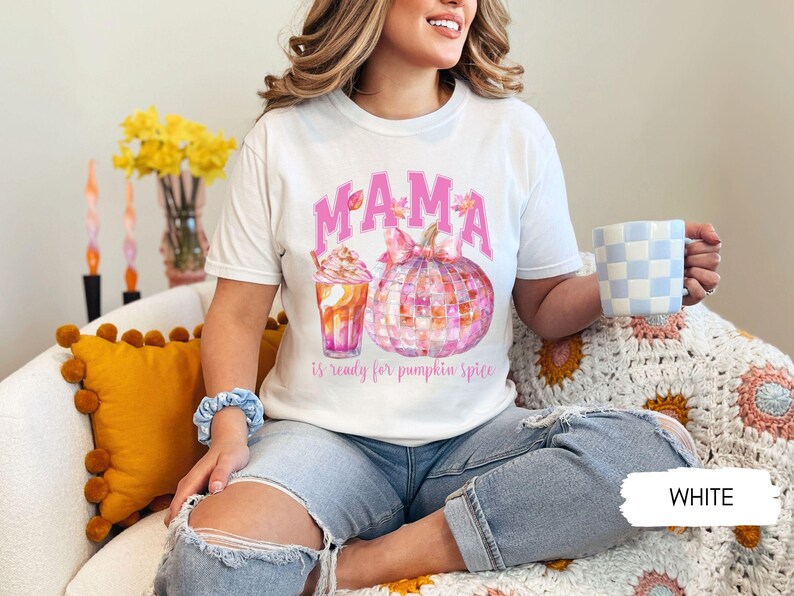 May include: White t-shirt with a pink "MAMA is ready for pumpkin spice" graphic featuring a pumpkin and a fall-themed drink.