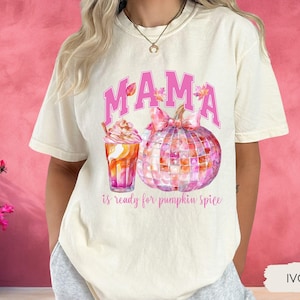 May include: A white t-shirt with the text "MAMA is ready for pumpkin spice" in pink lettering. The shirt features a watercolor illustration of a pumpkin and a cup of coffee.