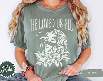 May include: A green t-shirt with a white graphic of Jesus with the text "He Loved Us All".