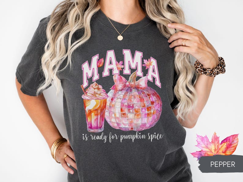 May include: A dark gray t-shirt with the text "MAMA is ready for pumpkin spice" in white. The shirt features a pink and white watercolor pumpkin with a pink bow and a pink and orange watercolor iced coffee.