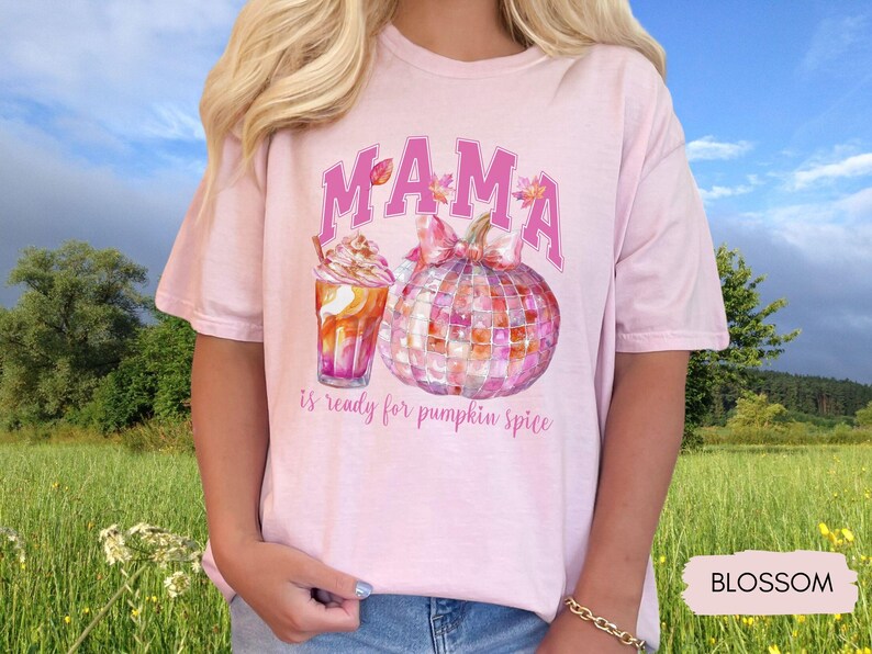 May include: Pink t-shirt with the text "MAMA is ready for pumpkin spice" in pink letters. The design features a watercolor pumpkin with a pink bow and a pink and orange iced coffee.