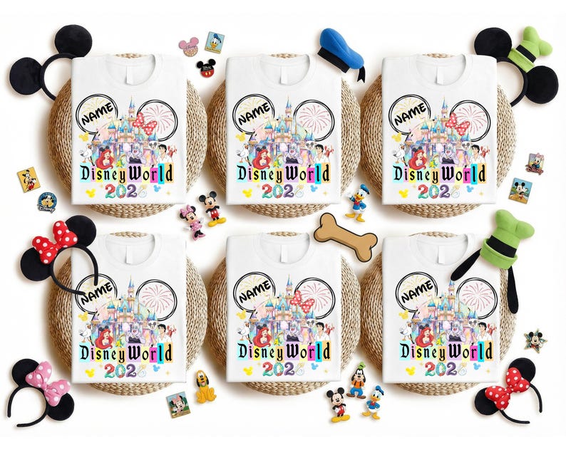 Puede incluir: Camisetas blancas con un dise&ntilde;o colorido de Disney World 2023, con un castillo, personajes y fuegos artificiales. Cada camiseta tiene un c&iacute;rculo "NAME" personalizable. Las camisetas est&aacute;n rodeadas de diademas con orejas de Mickey Mouse y figuras de personajes de Disney.