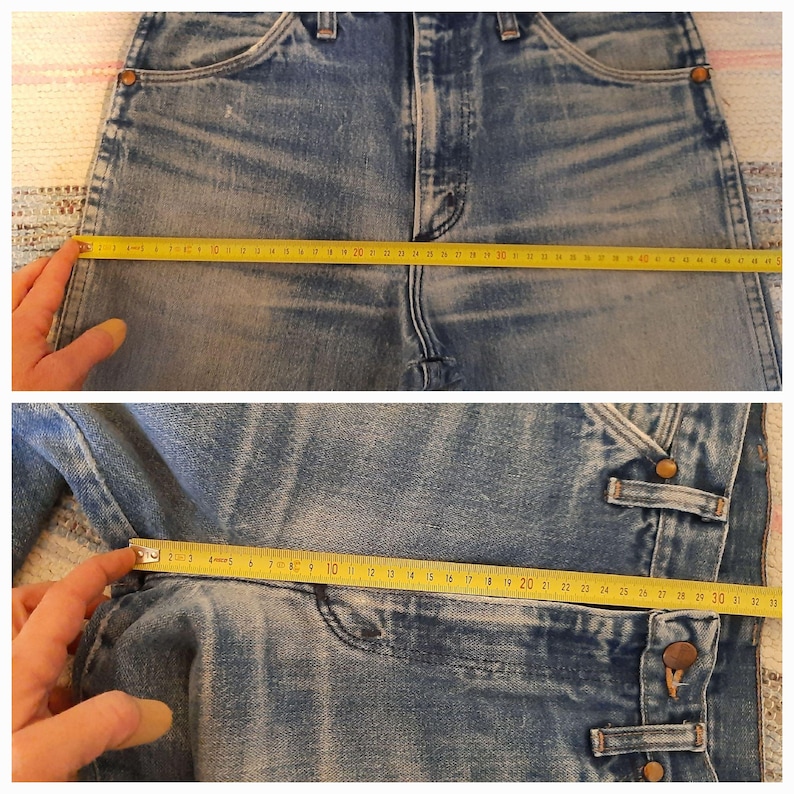 May include: Blue denim jeans featuring a high-waisted design with copper-toned rivets and a button fly. A yellow measuring tape is placed across the waist and hip areas, showing widths of approximately 18 inches and 12 inches respectively.