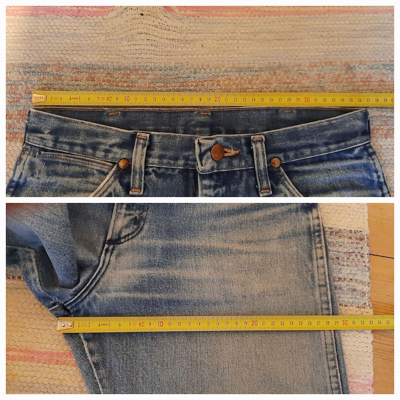 May include: Blue denim jeans featuring a button fly, belt loops, and copper-toned rivets. A yellow measuring tape placed across the waistband shows a width of approximately 15 inches, while a second tape across the thigh measures 11 inches.