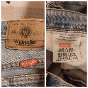 May include: Close-up of Wrangler Authentic Jeans. The jeans have a light blue wash and feature a brown leather patch with the Wrangler logo and text. The jeans are size 29 x 32.