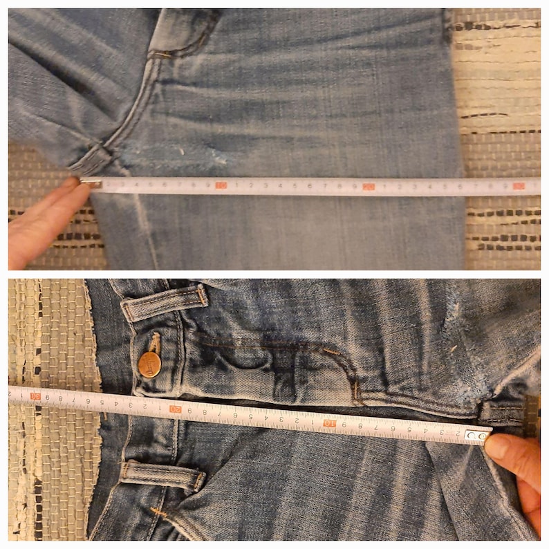 May include: Close-up of a pair of blue denim jeans with a copper button and a seam detail. A measuring tape is placed across the jeans to show the length.