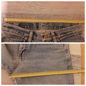 May include: Light blue denim jeans with a button closure and a metal rivet. A yellow measuring tape shows the waist and leg measurements. The jeans are laid flat on a patterned surface.