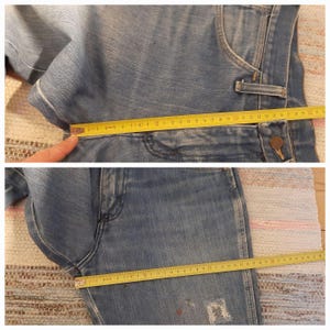Pode incluir: Jeans de ganga azul claro com fecho de bot&atilde;o e remendo desgastado. Uma fita m&eacute;trica amarela mostra as medidas da cintura e da perna. A cintura mede aproximadamente 76 cm, e a perna mede aproximadamente 51 cm.