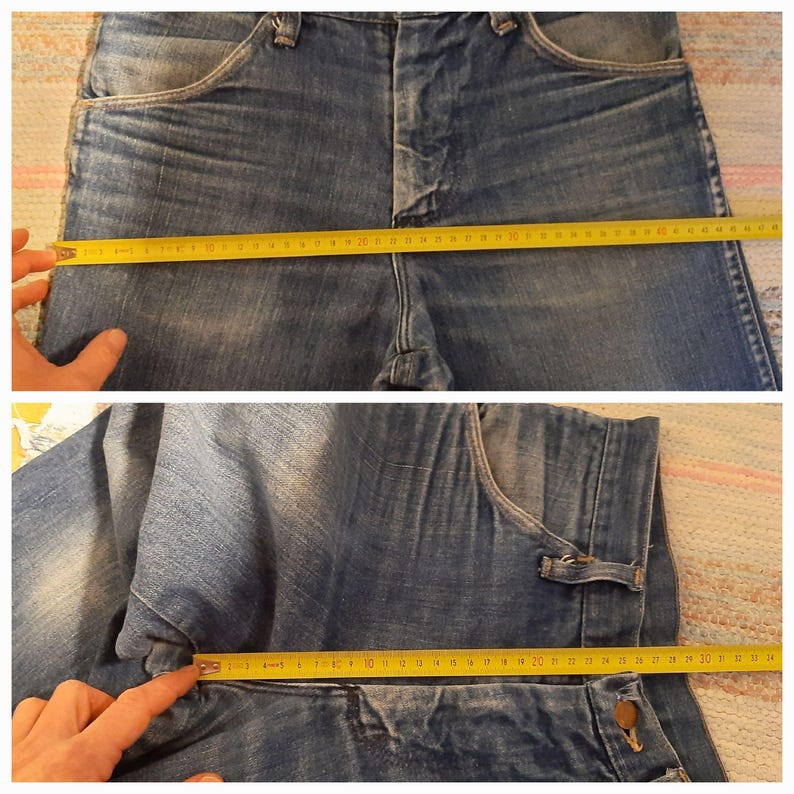 May include: Close-up of blue denim jeans with a yellow measuring tape showing the waist and inseam measurements. The jeans have classic five-pocket styling and a button and zipper closure. The waist measures approximately 47 inches.