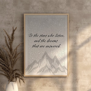 May include: A framed print with a quote from a book. The quote reads "To the stars who listen, and the dreams that are answered." The background of the print is a galaxy with stars and a light blue and gray color scheme.