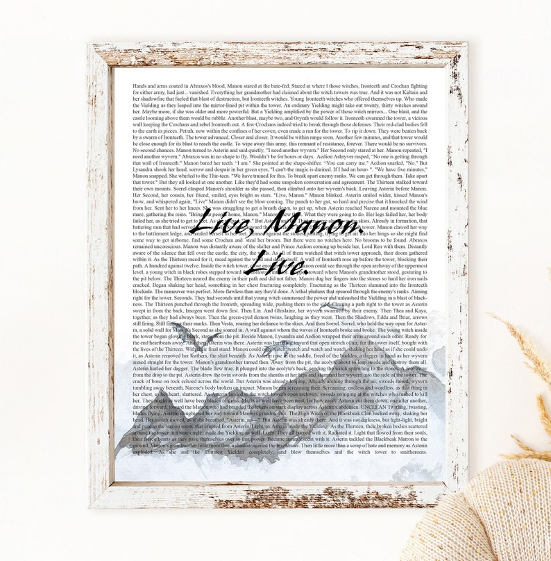 May include: A watercolor illustration of a mountain range with a quote from a fantasy novel. The quote reads "Live, Manon. Live." The text is in black and the mountains are painted in shades of gray and blue.