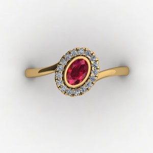Puede incluir: Un anillo de oro con una piedra ovalada roja rodeada por un halo de piedras blancas más pequeñas.