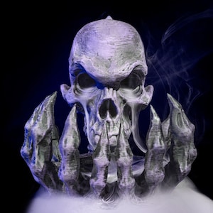 Puede incluir: Un cráneo gris detallado con una expresión amenazante, rodeado de un conjunto de manos con garras, todo emergiendo de una nube de humo blanco.