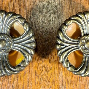 May include: Two ornate gold-toned cabinet knobs with a four-leaf clover design and a clear glass center.