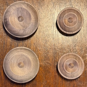 May include: Four wooden bowls of varying sizes, all with a concentric circle design. The bowls are arranged in a grid pattern on a wooden surface.