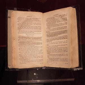 May include: An open antique book with yellowed pages. The book is titled "Exodus" and contains text from the Bible. The pages are worn and have a vintage feel.