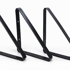 Könnte beinhalten: Drei schwarze Metall-Regalhalterungen in dreieckiger Form. Jede Halterung hat eine flache Basis mit vorgebohrten Löchern zur Montage und eine gebogene Oberseite. Die Halterungen sind zur Unterstützung von Regalen konzipiert und für verschiedene Einrichtungsstile geeignet.
