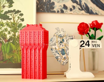 May include: A red 3D printed model of a building, a white calendar with the date "24 MAG VEN", and a bouquet of red roses.