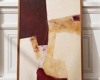 May include: Abstract art print in a wooden frame. The artwork features a composition of geometric shapes in burgundy, beige, and yellow hues. The framed art is leaning against a white wall with decorative molding, set on a hardwood floor.