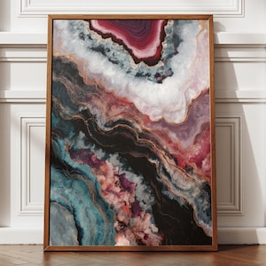 Könnte beinhalten: Gerahmter Kunstdruck mit einem abstrakten, geodenartigen Muster. Das Kunstwerk zeigt eine Mischung aus Farben, darunter Burgunderrot, Weiß, Türkis und Gold, in einem Holzrahmen. Der Druck wird vor einer weißen Wand präsentiert.
