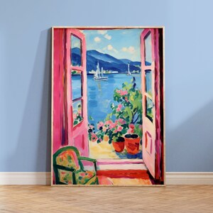 May include: A painting of a seascape viewed through a pair of open pink doors. The doors are framed in wood and lead to a balcony with a view of a blue body of water with mountains in the distance. There are two sailboats in the water and a potted plant with pink flowers on the balcony.