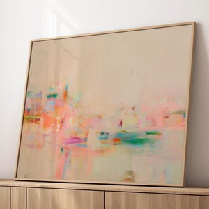 Könnte beinhalten: Ein rechteckiges gerahmtes abstraktes Gemälde mit einem weichen beigen Hintergrund und geschichteten Pinselstrichen in Rosa-, Orange-, Türkis- und Gelbtönen. Das Kunstwerk ist in einem dünnen Holzrahmen präsentiert.