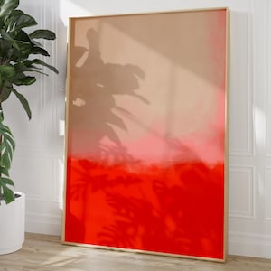Könnte beinhalten: Ein großer, gerahmter Kunstdruck mit einem Farbverlauf. Der obere Teil ist hellbraun, geht in Rosa über und dann in ein leuchtendes Rot am unteren Rand. Der Rahmen ist goldfarben. Das Kunstwerk lehnt an einer weißen Wand.