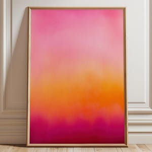 Könnte beinhalten: Ein gerahmter abstrakter Kunstdruck mit einem Farbverlauf. Das Kunstwerk wechselt von einem leuchtenden Rosa oben zu einem warmen Orange in der Mitte und tiefem Magenta unten. Der Rahmen hat eine hellbraune Farbe.