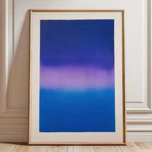 Könnte beinhalten: Abstrakter Kunstdruck in einem Holzrahmen. Das Kunstwerk zeigt einen Farbverlauf, der von tiefem Blau oben zu einem helleren Blau unten übergeht, mit einem lilafarbenen Band in der Mitte. Der Rahmen hat eine hellbraune Farbe.