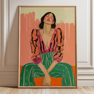 Puede incluir: Impresión artística enmarcada que representa a una persona sentada con los ojos cerrados. La figura lleva un top rosa y naranja de corte bajo con rayas negras, pantalones a rayas verdes y blancas, sobre un fondo melocotón y naranja. La obra está en un marco de madera.