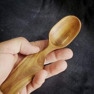 Op de afbeelding: Een houten lepel met een natuurlijke houten afwerking. De lepel is handgesneden en heeft een unieke vorm.