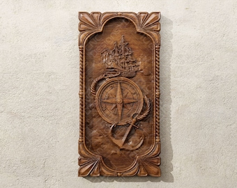 May include: A wooden wall plaque with a carved design of a ship, compass, and anchor. The plaque is framed with a decorative border and has a dark brown finish.