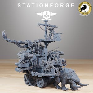 Könnte beinhalten: Ein graues Plastikmodell eines schwer bewaffneten, gepanzerten Fahrzeugs mit einer Totenkopf- und Knochenflagge. Das Fahrzeug verfügt über eine große Kanone, eine mit Spikes versehene Front und eine Besatzung aus Orks. Das Modell wird von Stationforge hergestellt und ist ein lizenziertes Produkt von Black Raven Factory.