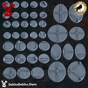 Op de afbeelding: Een set van 28 grijze plastic miniaturen voor tabletop games. De bases zijn rond en ovaal, met verschillende ontwerpen, waaronder een schedel, een rasterpatroon en een kruis. De bases zijn gemaakt door Black Raven Factory, een gelicentieerde printer.