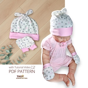 May include: A baby hat and matching mittens set featuring a white fabric with grey and pink polka dots and a solid pink cuff. The set is displayed alongside a doll wearing a matching hat, mittens, and a pink romper with a pacifier. Text reads: with Tutorial Video PDF PATTERN THUY SEWING PATTERN.