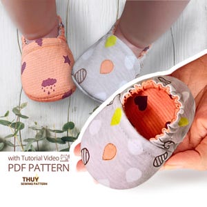 Pode incluir: Close-up de sapatos de bebé. Um sapato é cor de pêssego com um padrão de nuvens e estrelas roxas. O outro sapato é cinzento com bolinhas brancas e formas de folhas laranja. O interior do sapato é laranja. O texto "with Tutorial Video PDF PATTERN THUY SEWING PATTERN" é visível.