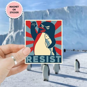 May include: A red, white, and blue poster with a penguin holding a fish. The penguin is wearing a red scarf and has a determined look on its face. The poster says "Resist" in large, white letters.