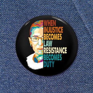 Puede incluir: Un botón negro con un retrato colorido de Ruth Bader Ginsburg y el texto "When injustice becomes law resistance becomes duty".