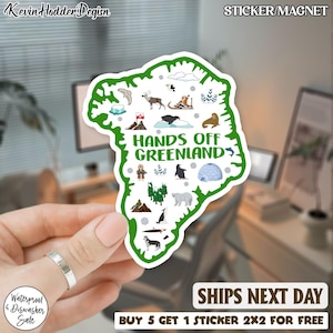 May include: A white sticker/magnet in the shape of Greenland, outlined in green, with illustrations of arctic animals and the text "HANDS OFF GREENLAND". The sticker also has the text "Waterproof & Dishwasher Sale".