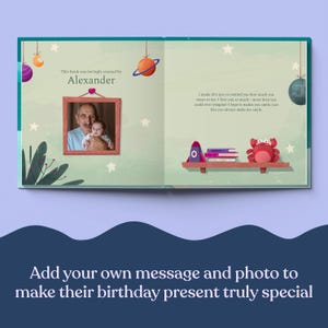 May include: A personalized book with a photo of an older man holding a baby. The book cover is green with stars and planets. The text on the cover reads "This book was lovingly created by Alexander".