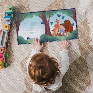 May include: A child's book open to a colorful illustration of forest animals and a child. The illustration features a deer, fox, bear, and butterflies. A wooden toy train is visible on the left. The child is lying on a patterned rug.