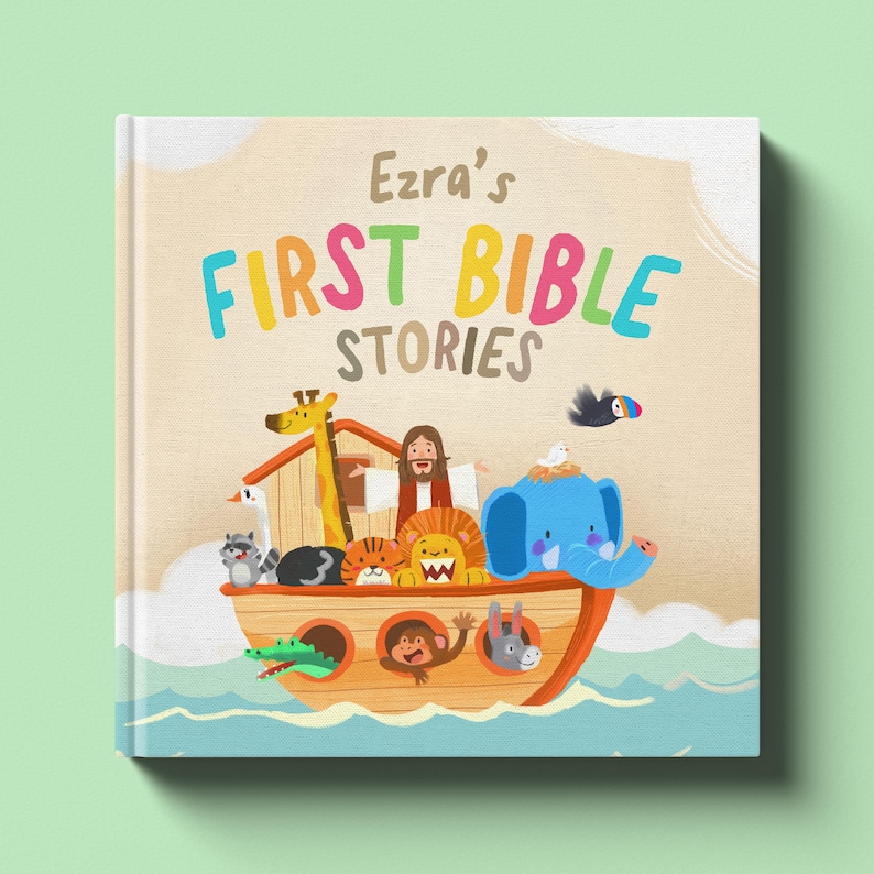 May include: A children's book titled "Ezra's First Bible Stories" features a colorful illustration of Noah's Ark with various animals. The cover has a light beige background with the title in bright, playful lettering. The ark is depicted on water with a light green background.