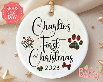 May include: White ceramic Christmas ornament with a marble pattern. It features the text "Charlie's First Christmas 2023" with a red heart, a snowflake, a paw print, and a bone.