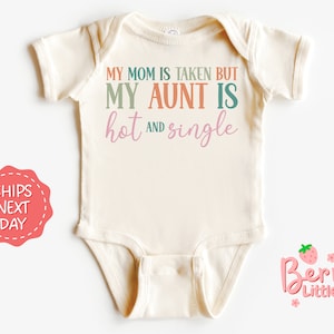 May include: A white baby onesie with the text "My mom is taken but my aunt is hot and single" in colorful letters. The onesie is on a white background with a pink and green strawberry logo in the bottom right corner.