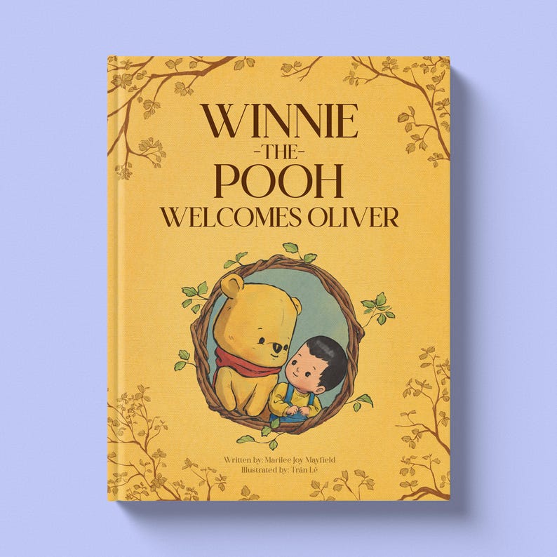 Pode incluir: Um livro de capa dura intitulado "Winnie the Pooh Welcomes Oliver" com uma capa amarela. A capa apresenta uma ilustra&ccedil;&atilde;o de Winnie the Pooh e um menino. O livro tem galhos e folhas decorativas.