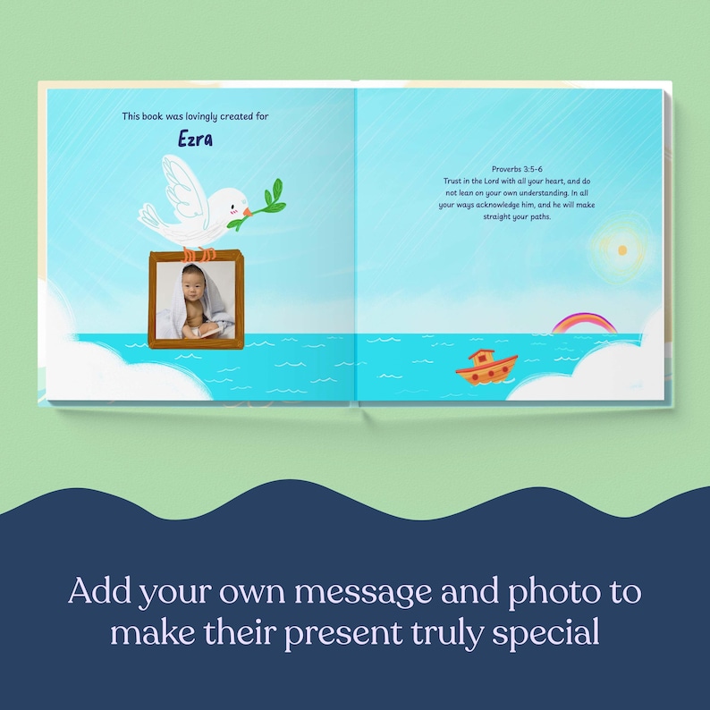 May include: Open book with a personalized page for "Ezra." A white dove with a green sprig sits above a framed photo. The book features a blue sky and sea illustration with a small orange boat and a rainbow. Text reads "This book was lovingly created for Ezra."