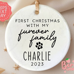 May include: White round Christmas ornament with a marble pattern. It says "First Christmas with my furever family Charlie 2023".