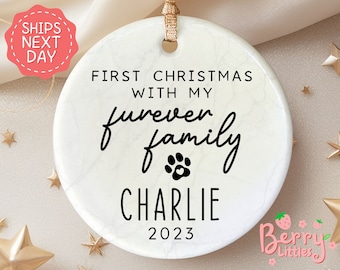 May include: White round Christmas ornament with a marble pattern. It says "First Christmas with my furever family Charlie 2023".