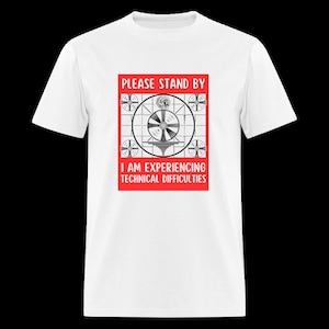 Op de afbeelding: Wit T-shirt met een rode afbeelding van een vintage televisie-testpatroon. De tekst op de afbeelding luidt "PLEASE STAND BY I AM EXPERIENCING TECHNICAL DIFFICULTIES".